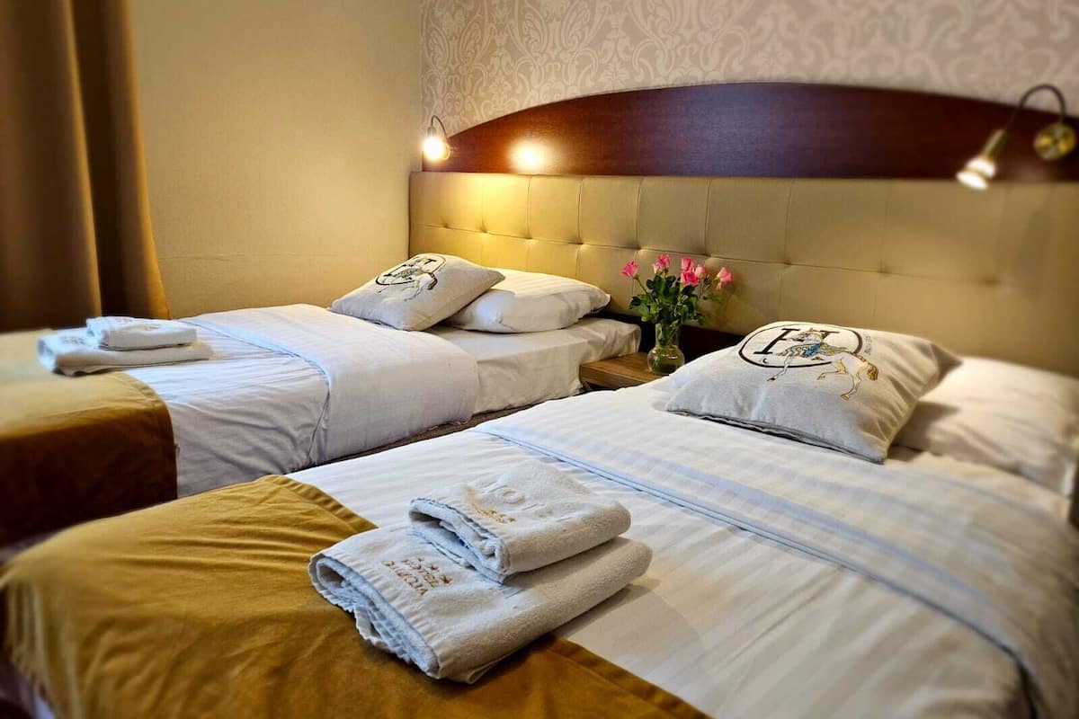 A hotel room with two beds, each with neatly folded towels and pillows.