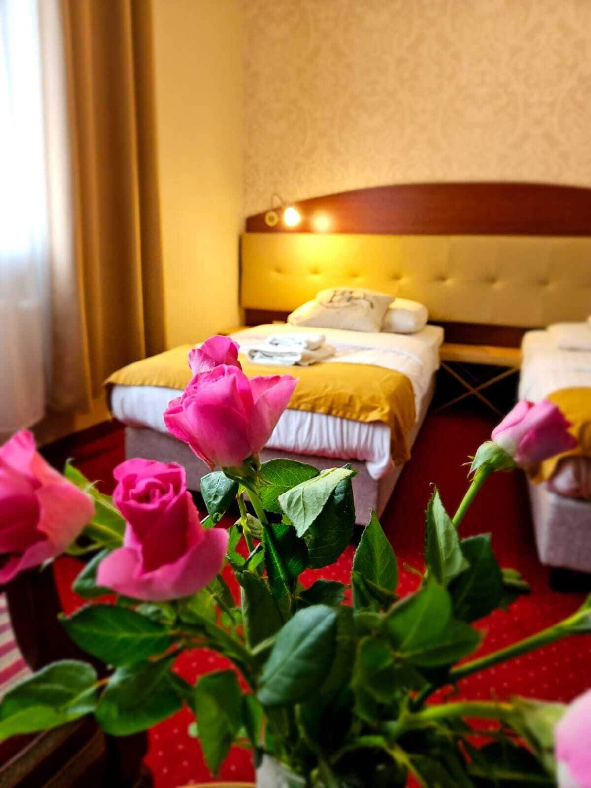 A hotel room with a bed, a headboard, and a window with curtains.