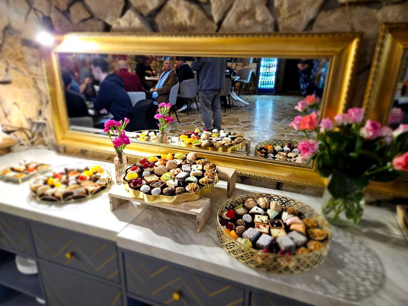 A buffet table with various desserts and a mirror reflecting the room.