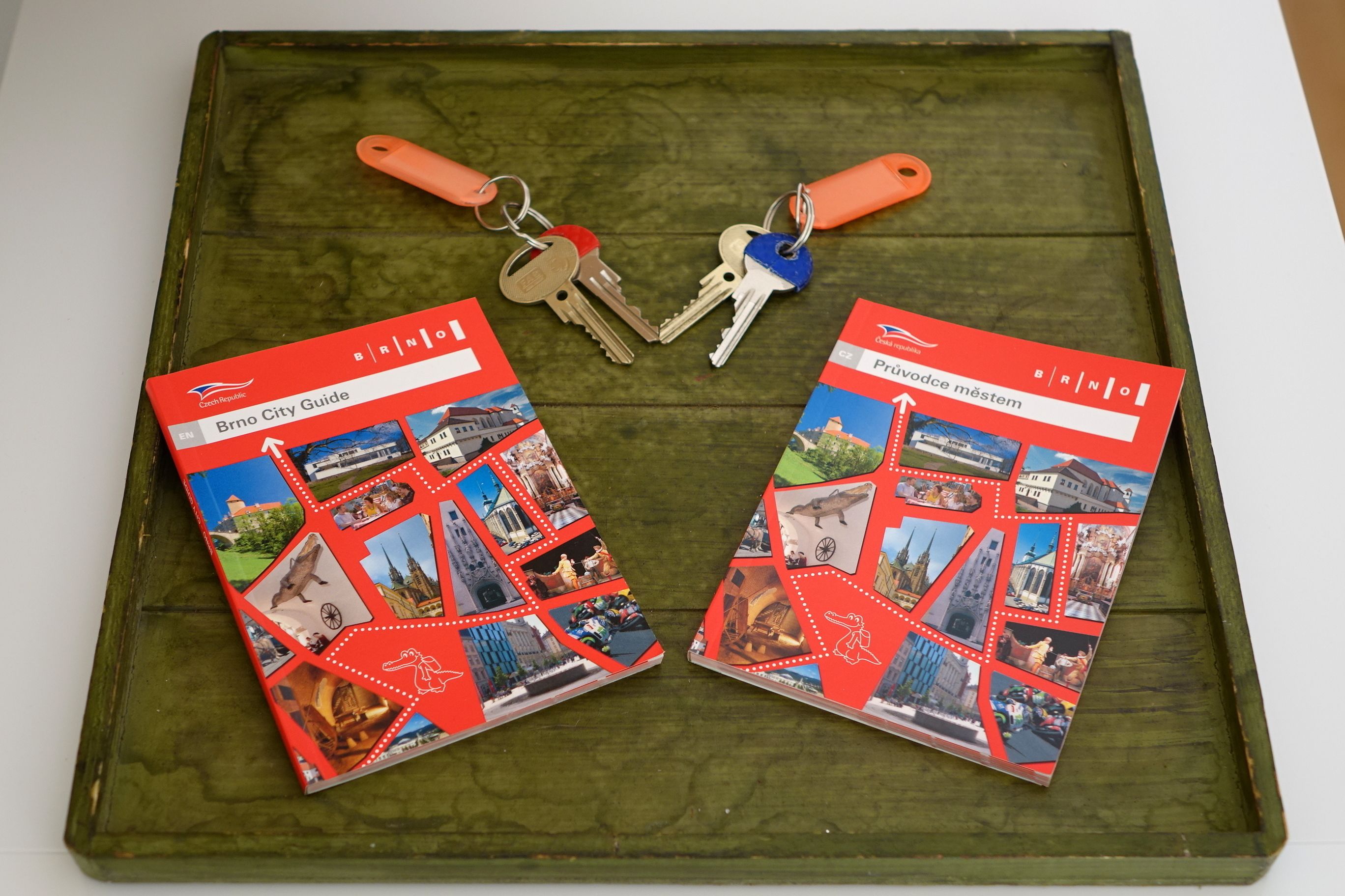 Two travel guides with keys on a wooden tray.
