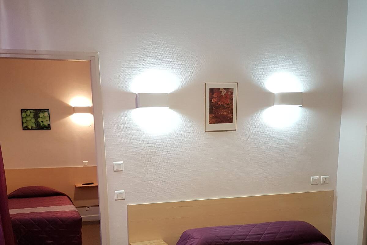 A hotel room with two beds, a small desk, and a chair.
