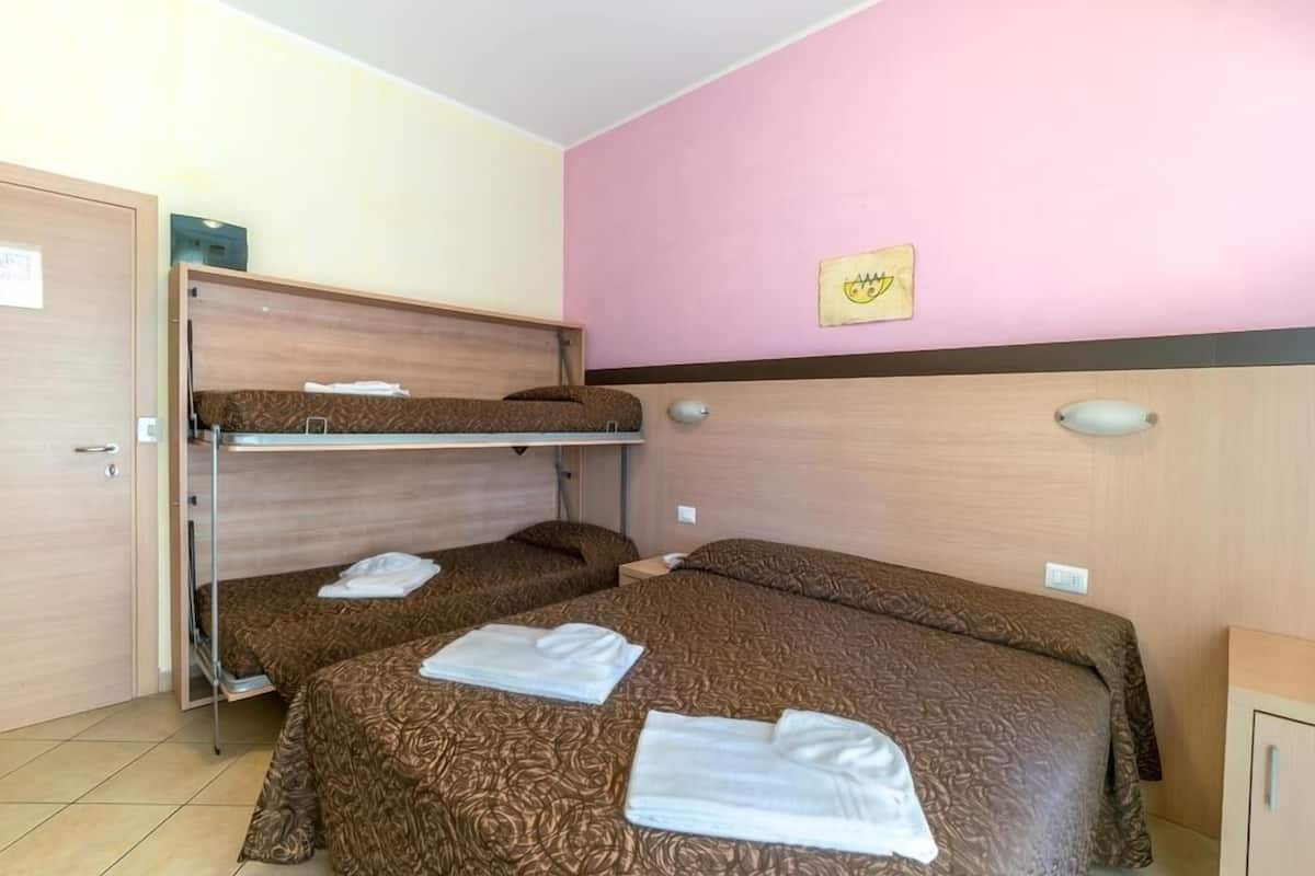 A hotel room with bunk beds, a pink wall, and a framed picture.