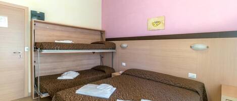 A hotel room with bunk beds, a pink wall, and a framed picture.