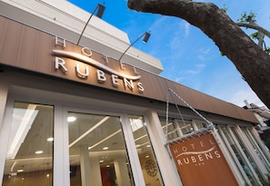 Un letrero de hotel con el nombre "Hotel Rubens" y un amplio ventanal con un reloj.