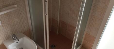 A bathroom with a glass-enclosed shower, a white sink, and tiled walls.