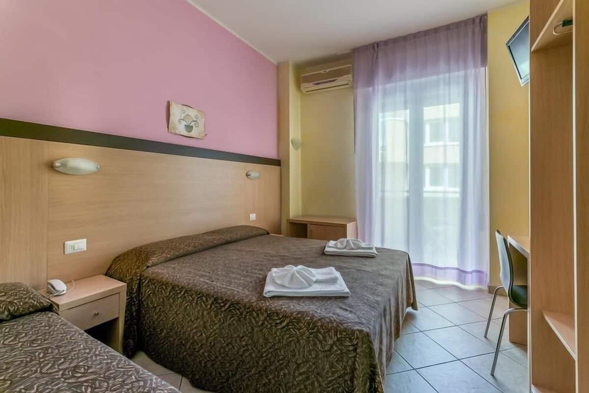 A hotel room with a bed, a bedside table, a chair, and a TV.