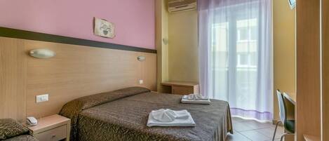 Una habitación de hotel con una cama, una mesita de noche, una silla y un televisor.