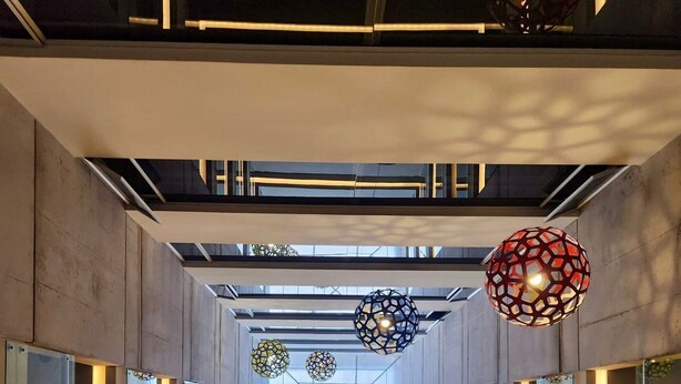 A modern architectural interior with a geometric design, featuring a central glass corridor and hanging spherical light fixtures. - Hotel Finlandia (Quito)