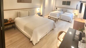 A hotel room with two beds, a desk, and a chair. There is a painting on the wall and a ceiling light. - Hotel Finlandia (Quito)