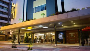 A hotel entrance with a modern design, a visible staircase, and outdoor seating area. - Hotel Finlandia (Quito)