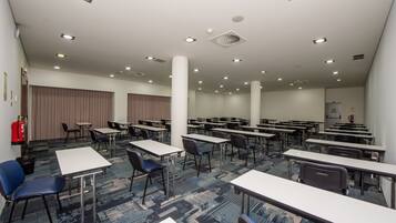 Un salón de conferencias con varias mesas y sillas, un extintor y una alfombra estampada.