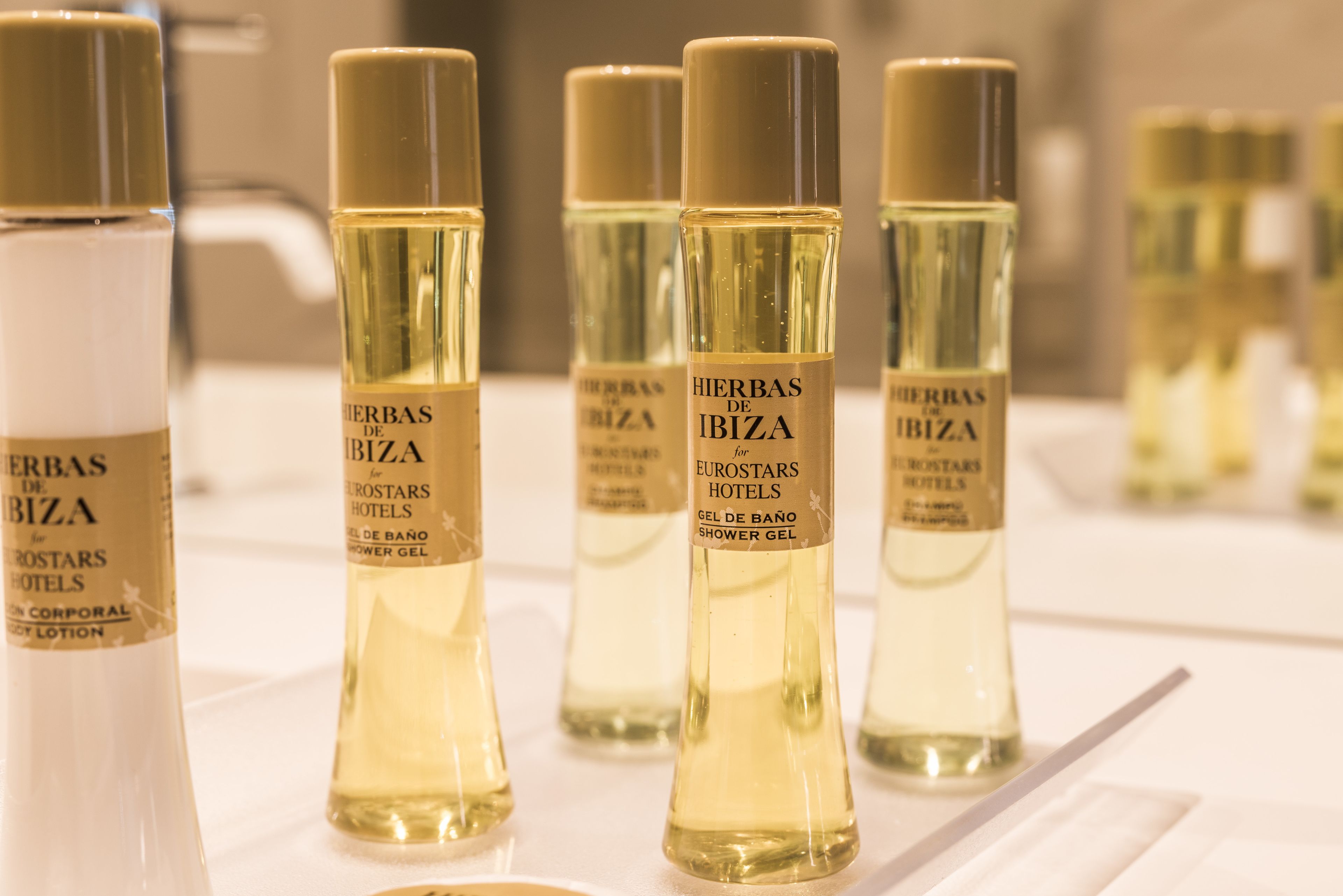 Botellas de gel de ducha con la etiqueta "Herbas de Ibiza" sobre una superficie blanca.