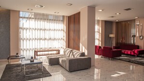 A modern hotel lobby with a sectional sofa, a small table, and red chairs.