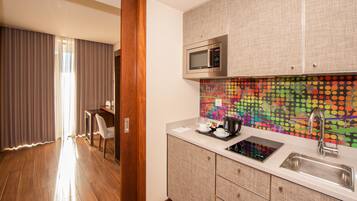 A modern kitchen with a microwave, sink, and a colorful dot-patterned backsplash.