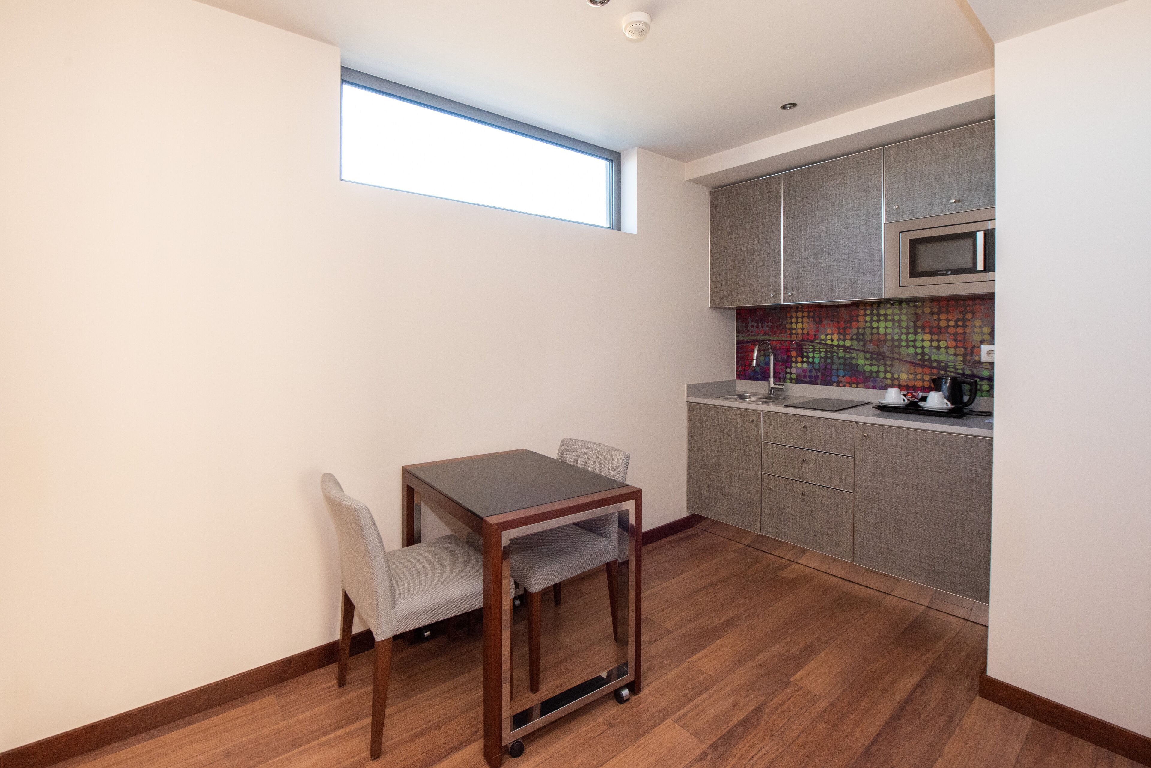 A compact kitchen with a dining area, a microwave, and a colorful backsplash.