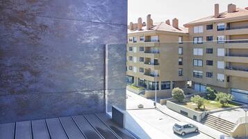A modern building with a balcony overlooking a parking area and residential buildings.