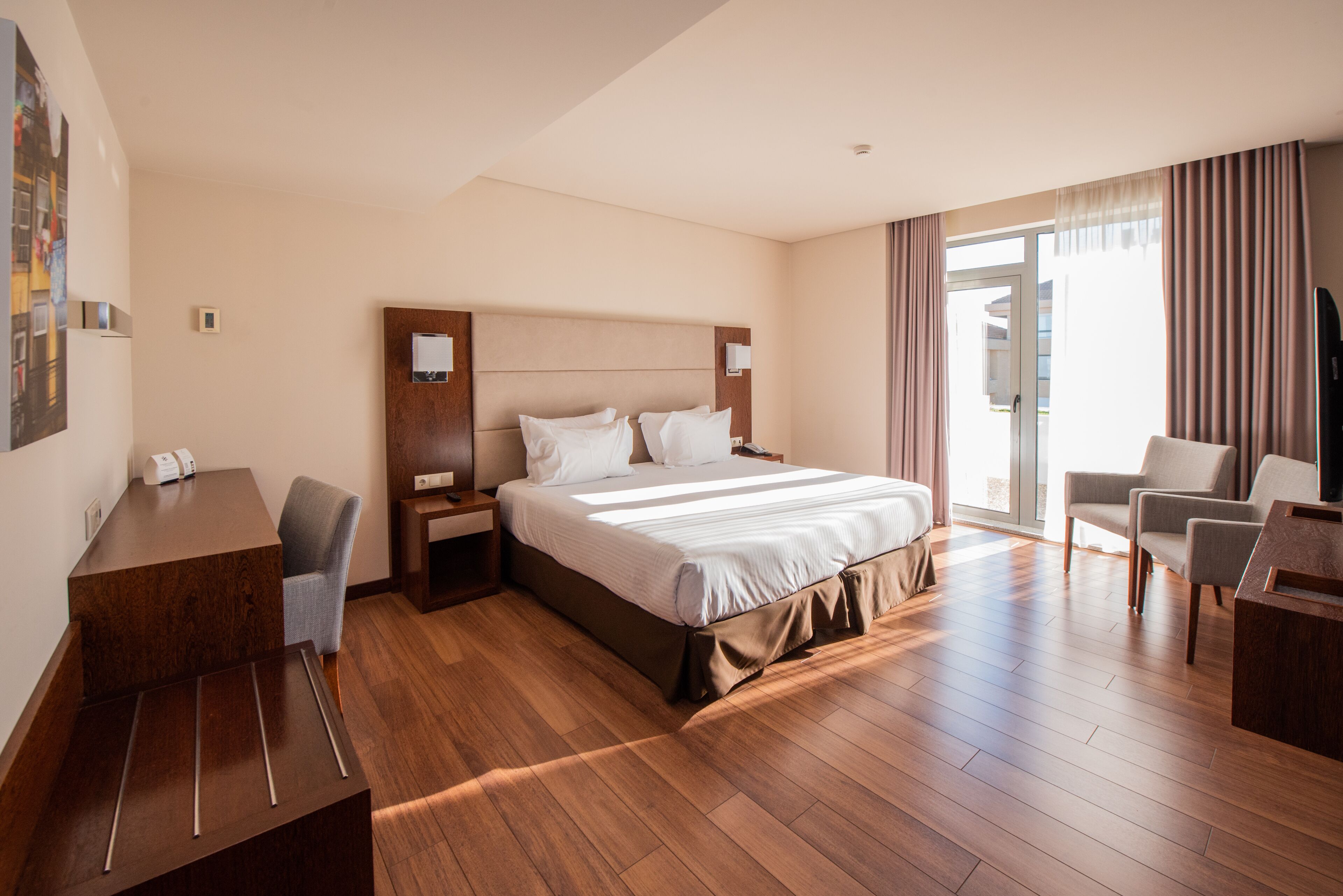 A hotel room with a large bed, a desk, and a chair.
