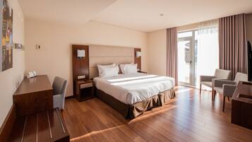 A hotel room with a large bed, a desk, and a chair.
