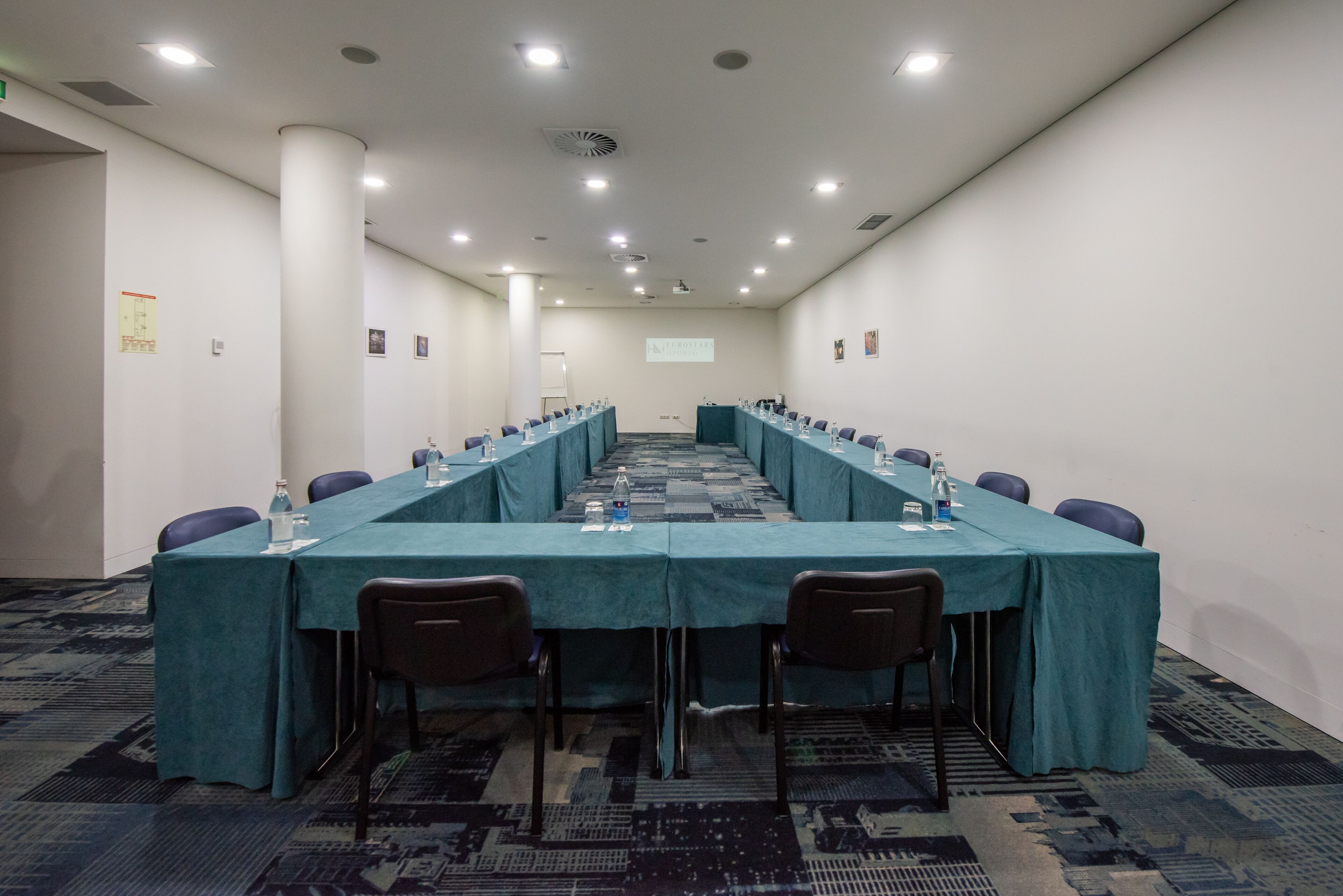 A conference room with a long table, chairs, and a projector screen.