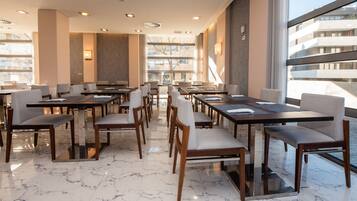 Un espace de restauration moderne avec un sol en marbre, des tables et des chaises en bois.
