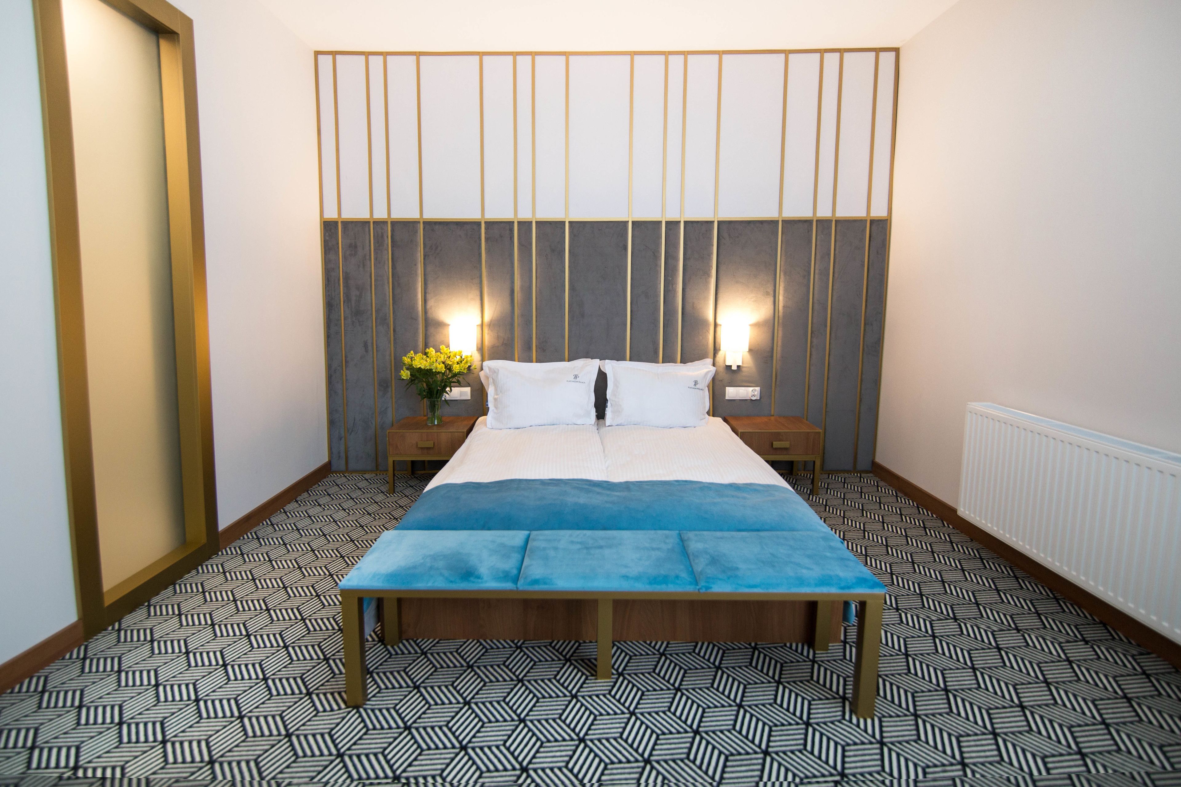 Un dormitorio con cama, mesitas de noche y suelo estampado.