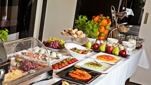 A buffet table with various food items including fruits, vegetables, and pastries.