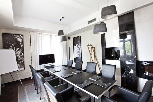A modern conference room with a long table, black chairs, and a whiteboard.