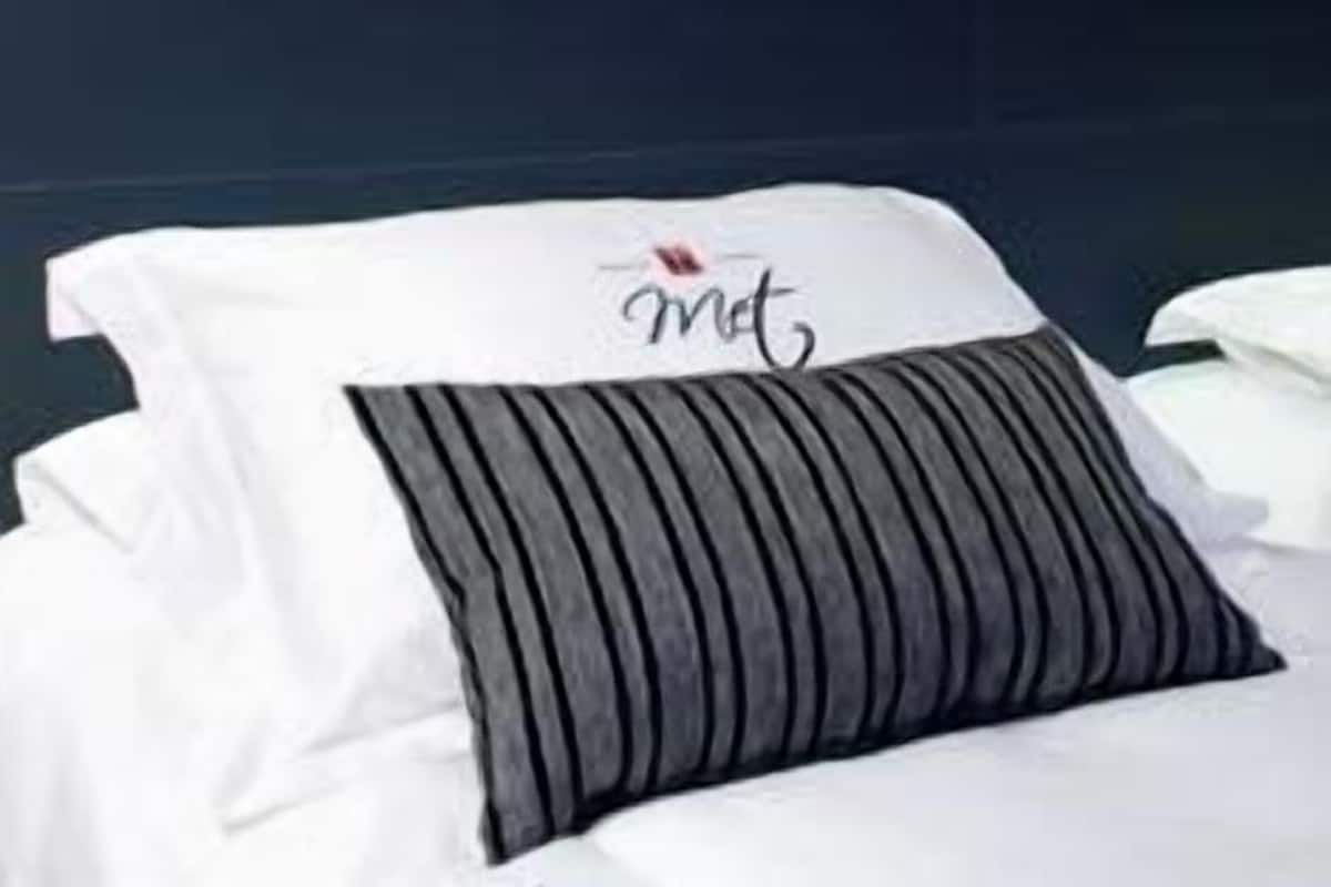 A hotel room with a bed, a headboard, and a piece of abstract art on the wall.