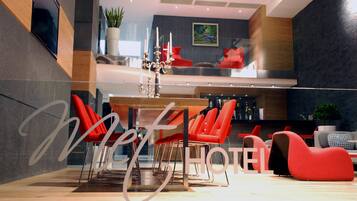 Un moderno vestíbulo de hotel con un comedor que presenta sillas rojas y una mesa de madera.