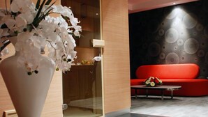 A modern interior with a large white vase of white flowers, a red sofa, and a patterned wall. - Met Boutique Hotel - Boutique Class (Izmir)