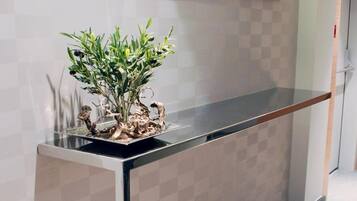 A reception desk with a checkered wall design, a potted plant, and a mirror above it.