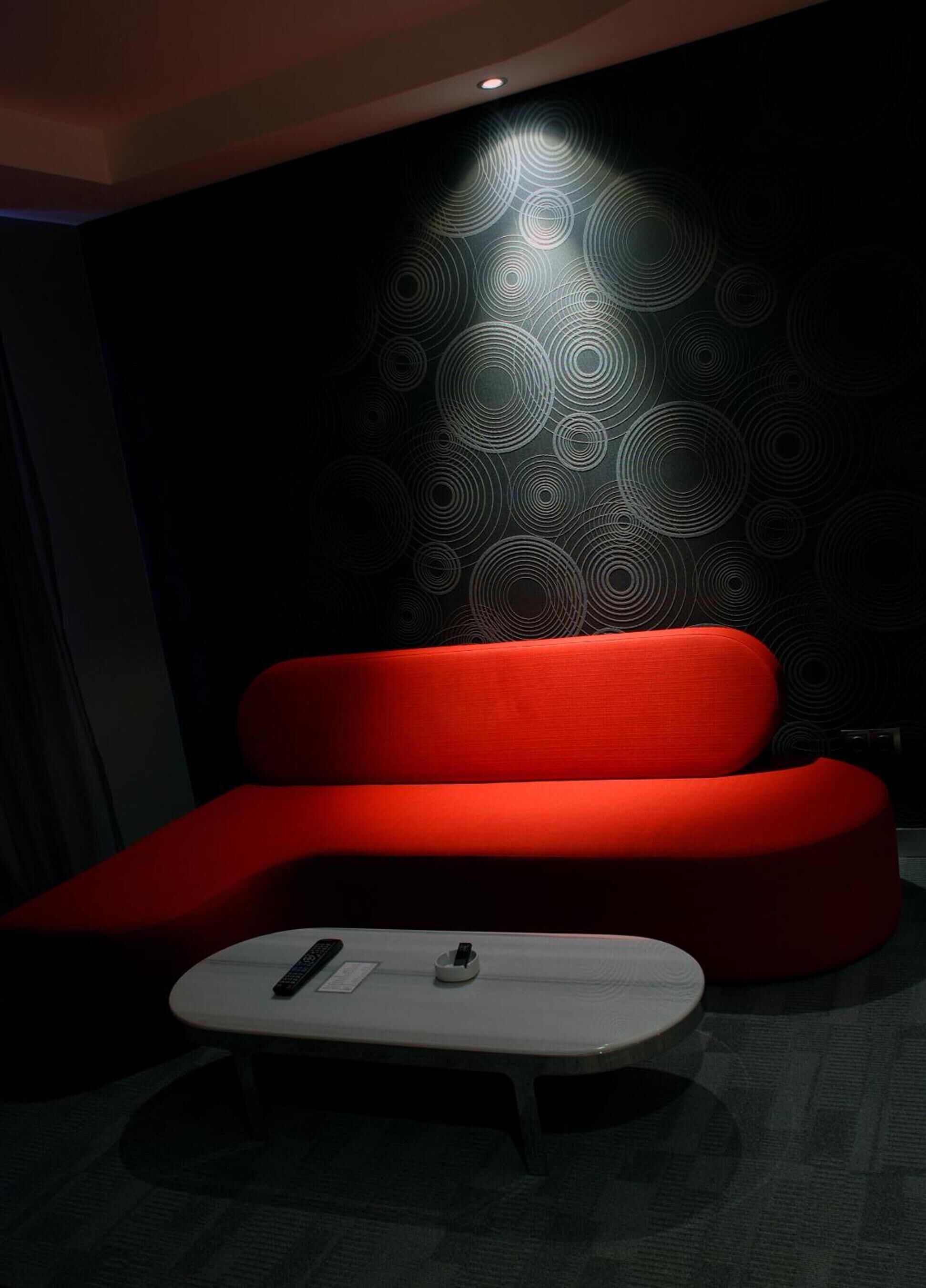 Una sala de estar moderna con un sofá rojo y una pequeña mesa de centro blanca.