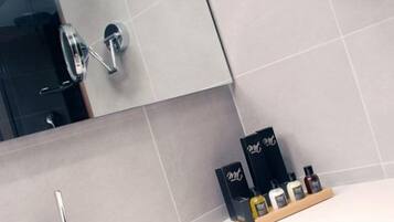 Un bany amb un lavabo modern, un mirall i productes de tocador a la superfície.