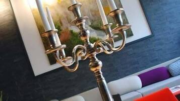 A candelabra with four candles on a wooden table in a modern living room with a gray sofa and colorful cushions.