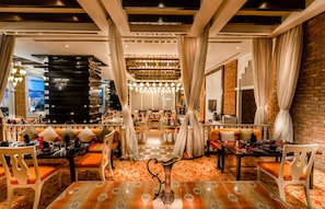 A modern dining area with a central table, cushioned seating, and a decorative centerpiece.