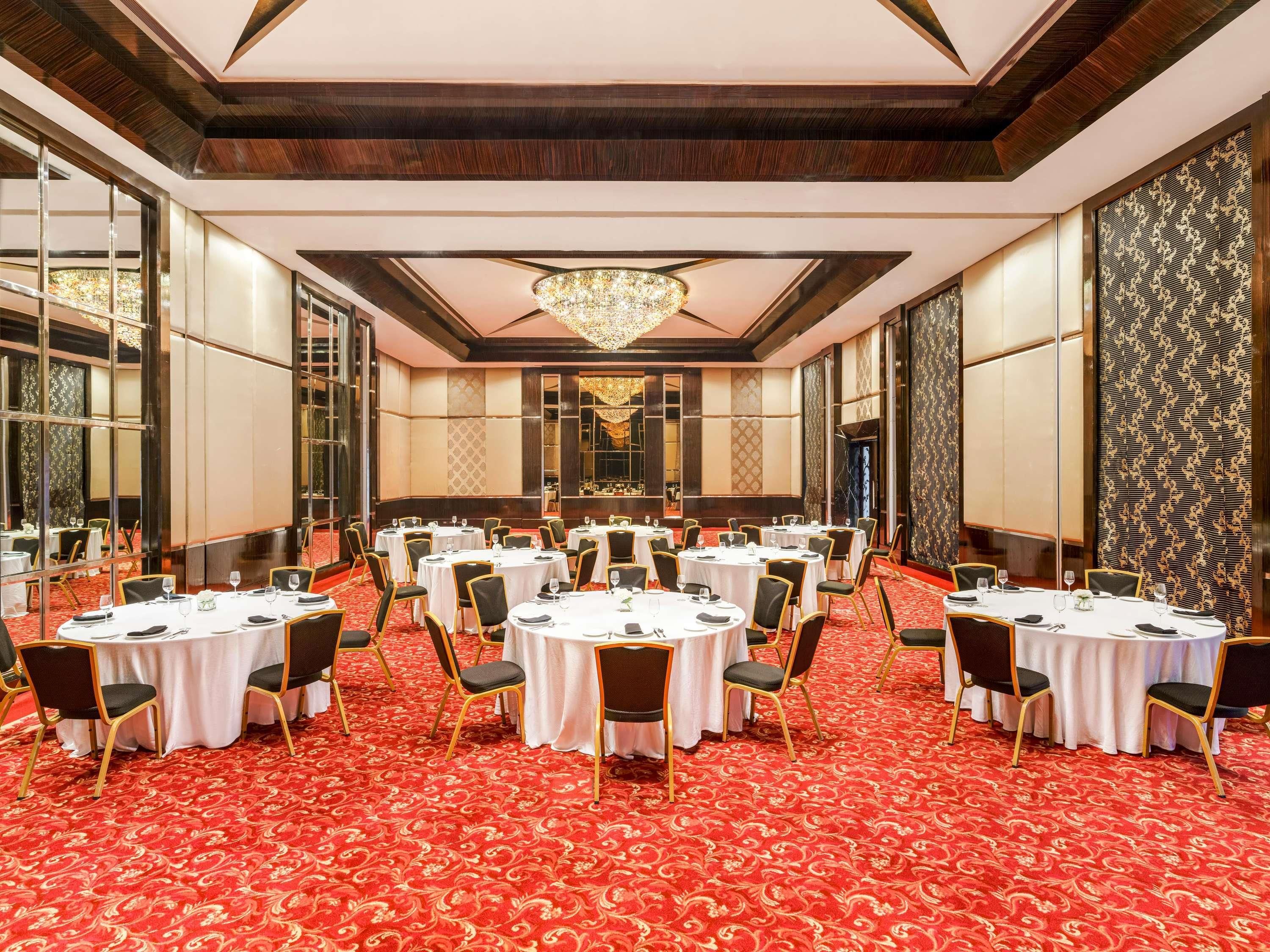 Un salón de banquetes con mesas redondas, sillas y un suelo cubierto de alfombra roja.