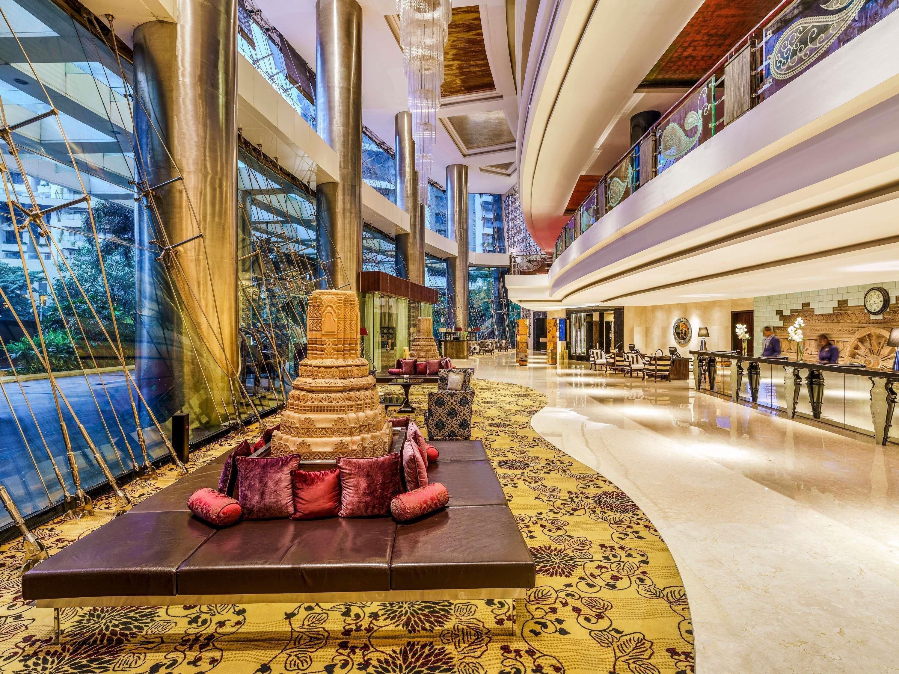 A spacious lobby with a central decorative structure, a seating area with patterned rugs, and a reception desk.