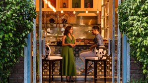 A restaurant with a bar area, a chef, and a woman in a green dress. - Sofitel Mumbai BKC Hotel (Mumbai)