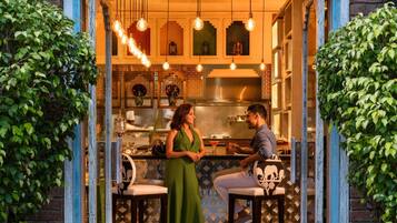 Un restaurant avec un bar, un chef et une femme portant une robe verte.