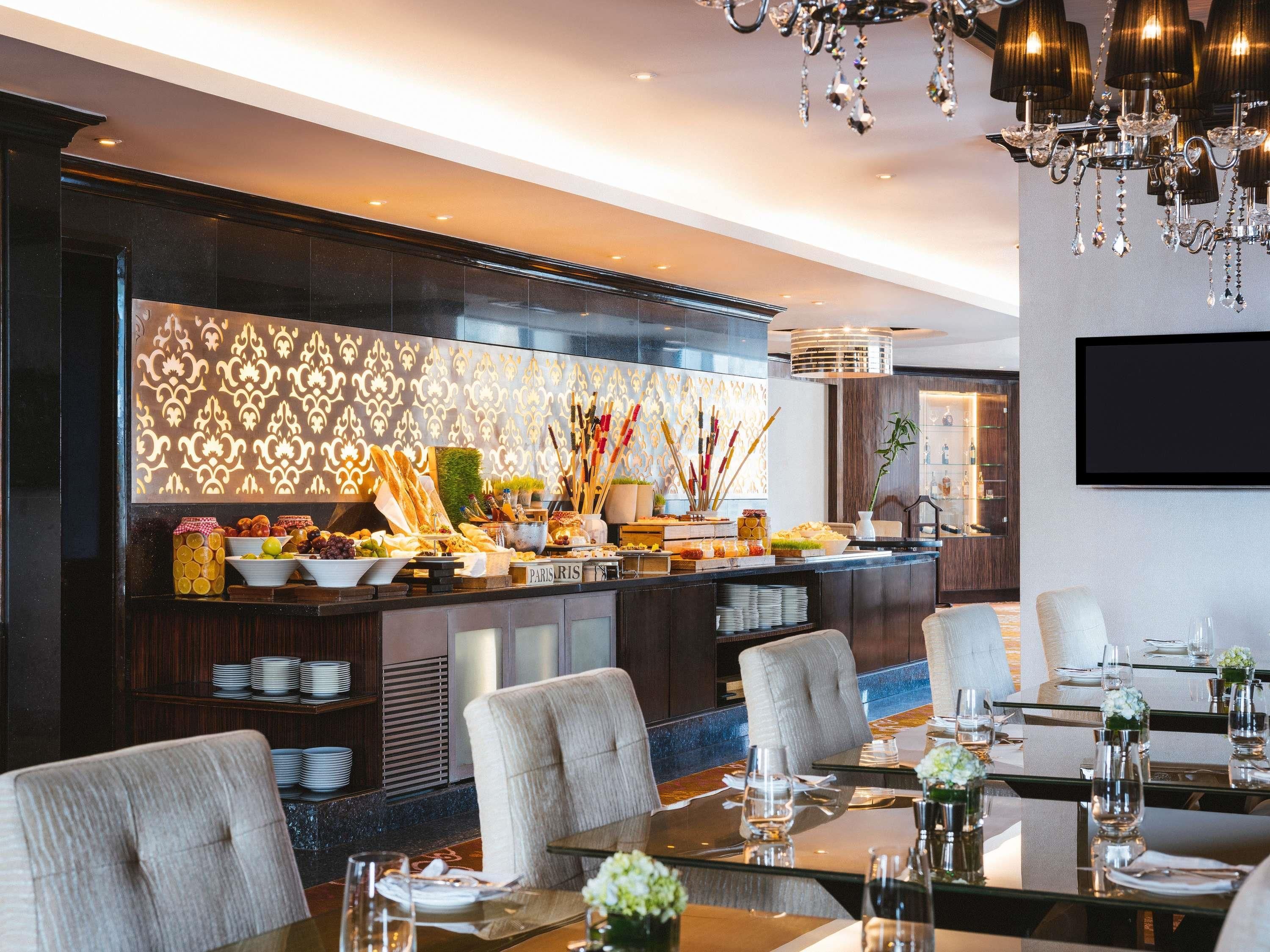Ein moderner Essbereich mit Buffet, einer Chandelüster und einem an der Wand befestigten Flachbildfernseher.