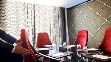 A conference room with a glass table, red chairs, and a patterned wall.