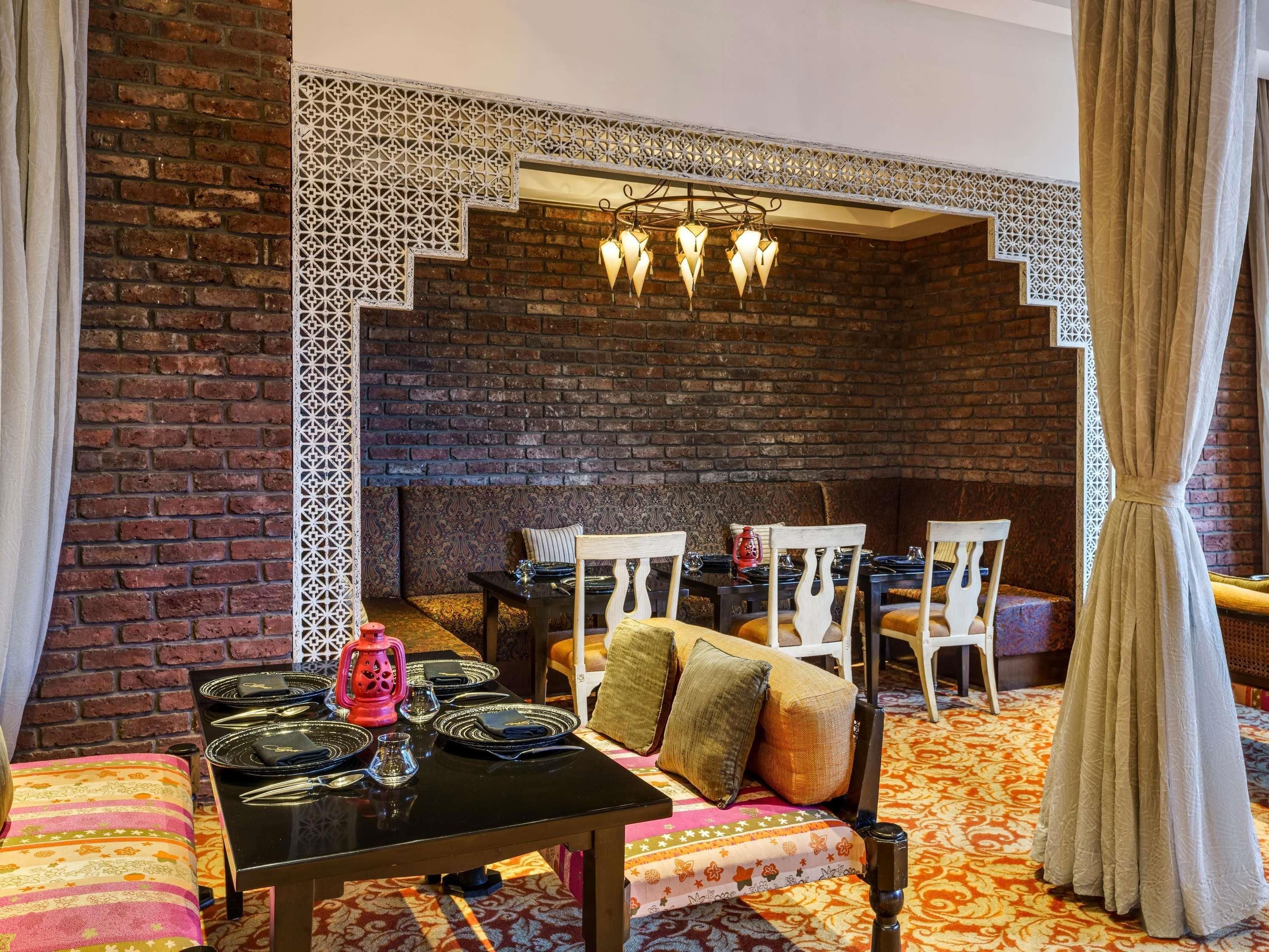 A cozy interior with a brick wall, a patterned ceiling, and a dining area with a table set for four.