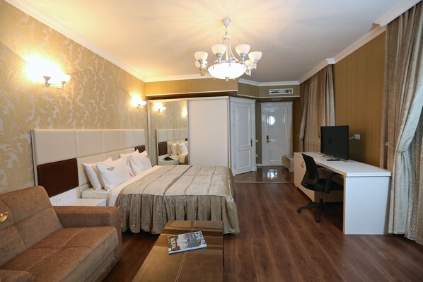 A hotel room with a bed, a sofa, a desk, a television, and a mirror.