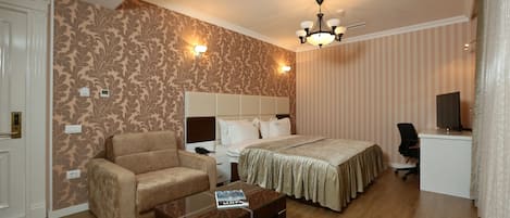 Quarto de hotel com cama, sofá, escrivaninha e mesa de centro.