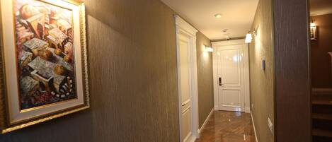 A hallway with a framed artwork on the left, a door at the end, and a staircase to the right.