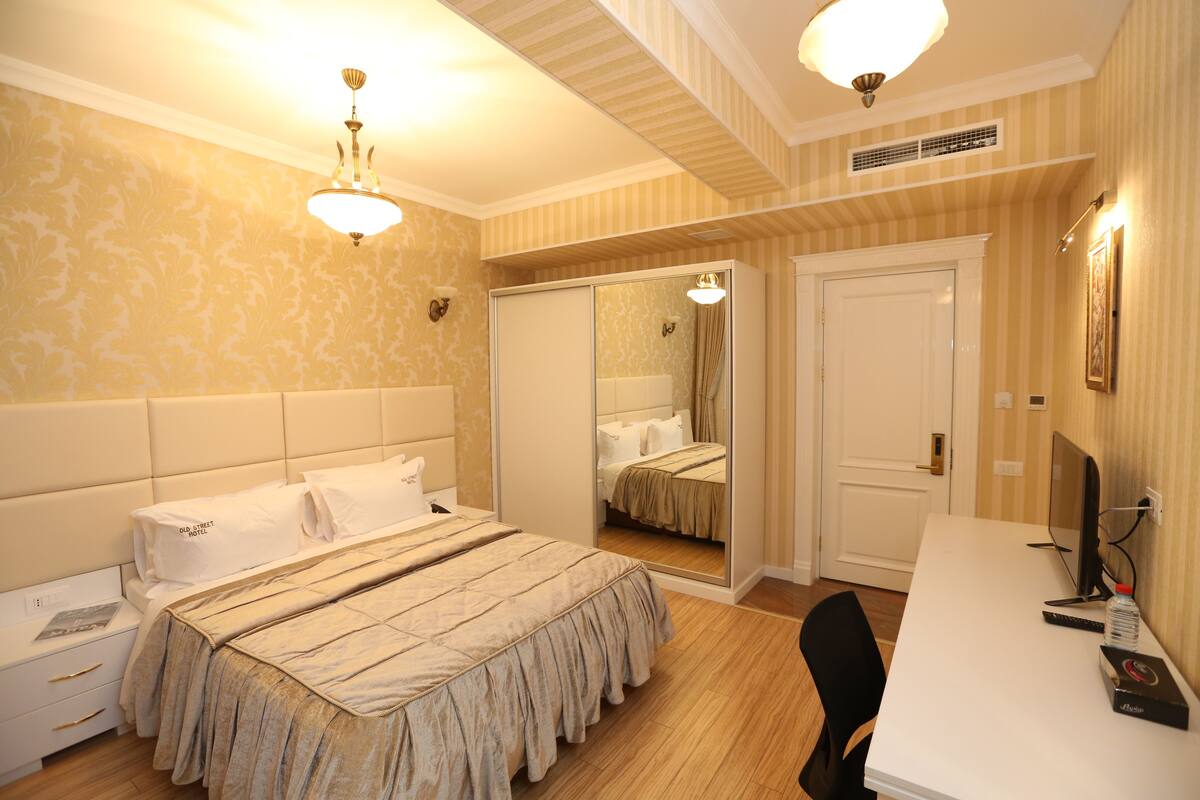 Een hotelkamer met een bed, een bureau, een stoel, een spiegel en een deur.