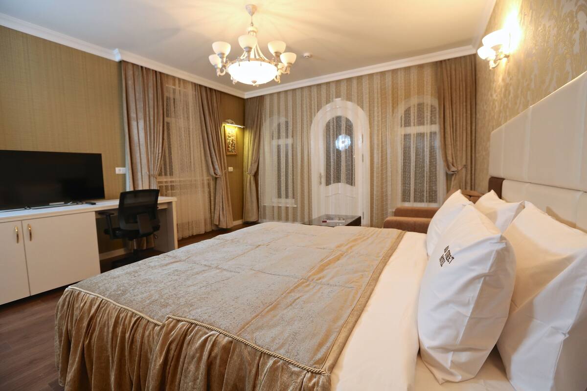 Een hotelkamer met een groot bed, een bureau met een televisie en een stoel.