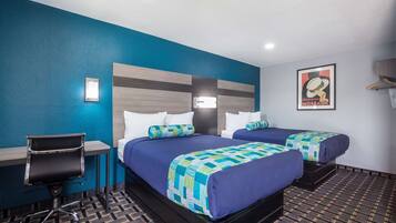 A hotel room with two beds, a desk, and a chair.