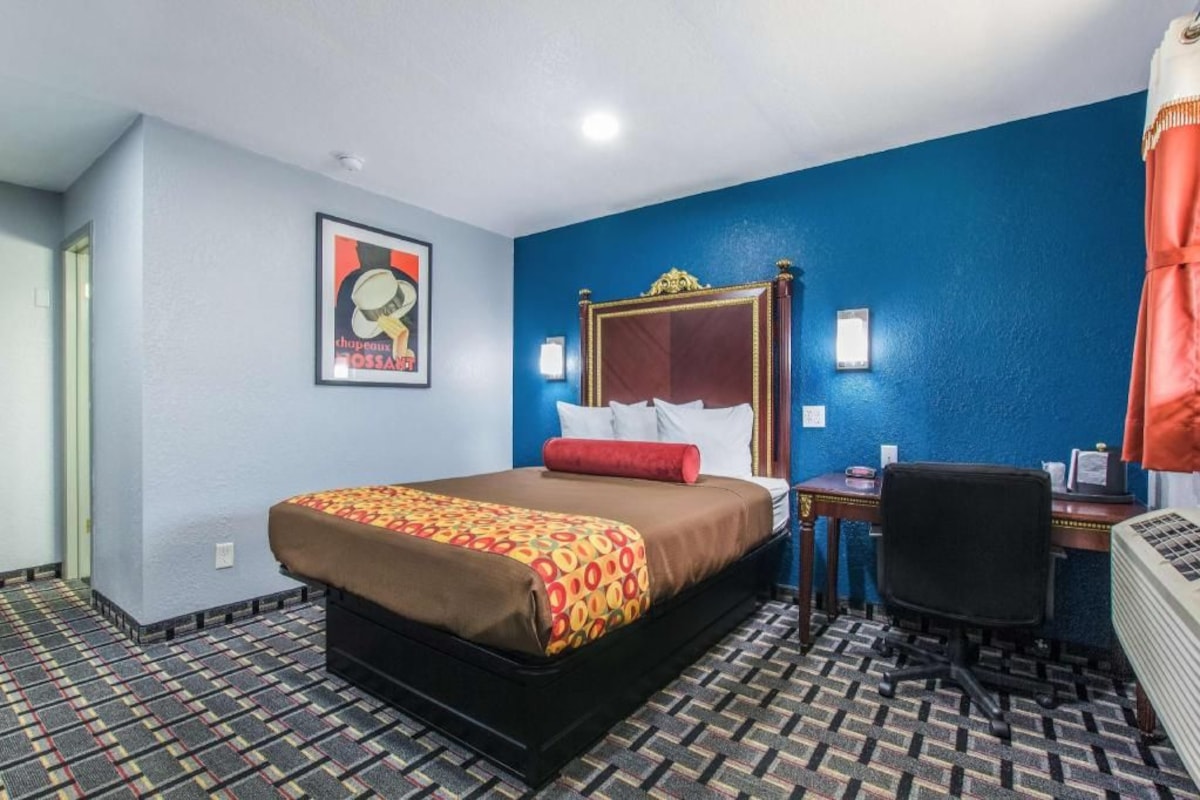 A hotel room with a large bed, a desk, and a chair.