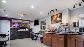 Une cuisine moderne dotée d’un coin café, d’un mur décoratif en pierre et d’un espace détente avec des chaises.